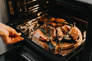 The process of baking marinated meat in a home oven. Three pieces of lard seasoned with spices and greens for roasting pork.