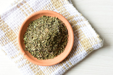 Chopped dried leaves of basil leaves on white wooden background