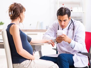 Young doctor checking pregnant woman's blood pressure