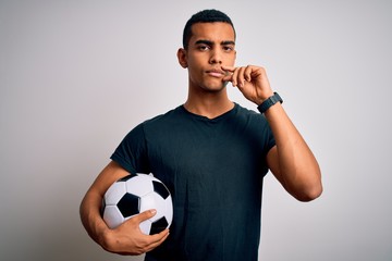 Handsome african american man playing footbal holding soccer ball over white background mouth and...