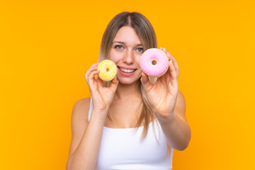 Young blonde woman over isolated blue background holding donuts with happy expression