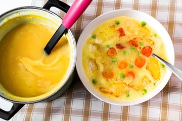 Creamy vegetable soup from celery, carrot and peas, pot.