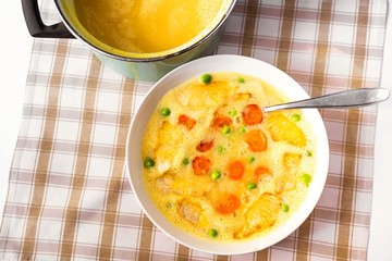 Creamy vegetable soup from celery and carrot with green pea, closeup.