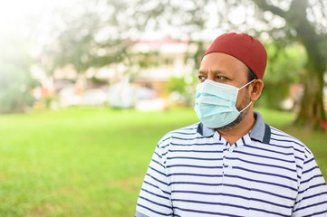 Senior Asian Muslim Man in medical mask, side view of attractive male looking straight ahead. Health care and medical after covid-19 concept. Copy space.