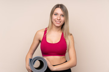 Young sport blonde woman over isolated background with a mat and smiling