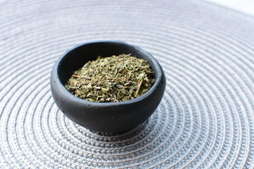 Chopped dried leaves of basil leaves on white wooden background