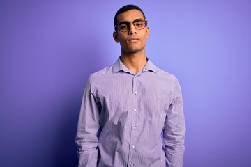 Handsome african american man wearing striped shirt and glasses over purple background looking sleepy and tired, exhausted for fatigue and hangover, lazy eyes in the morning.