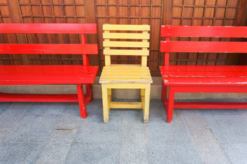 Red and Yellow wooden bench chairs in the park.