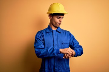 Young handsome african american worker man wearing blue uniform and security helmet Checking the...
