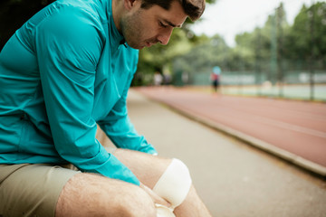 Fit young men taking rest from running. Two friends training outdoors.