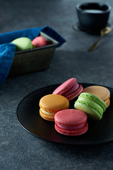 Macaroons lying on a black plate. Tasty sweet dessert, food photography