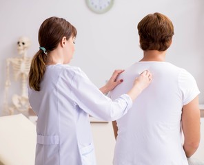 Obraz premium Male patient visiting young female doctor chiropractor