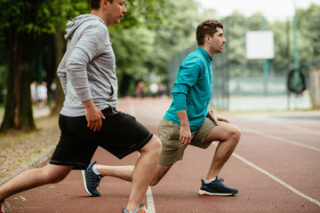 Young men exercising on a race track. Two young friends training outdoors.