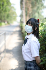 Naklejka premium Asian school girl with mask in urban city on tree background