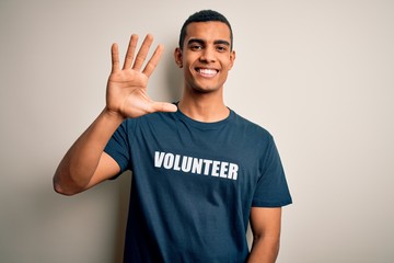 Young handsome african american man volunteering wearing t-shirt with volunteer message showing and...