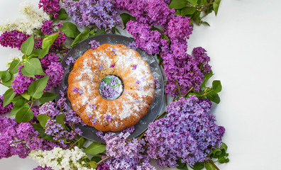 Cake with purple lilac flowers. Beautiful Homemade cupcake  and a bouquet of lilacs on a purple...