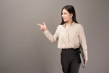 Portrait of Beautiful business woman is showing something on gray background