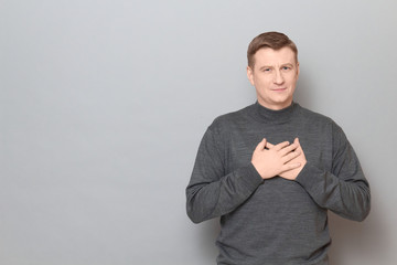 Portrait of man holding hands on chest and thanking somebody