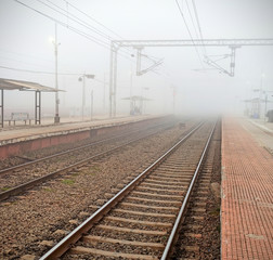 Obraz premium empty rail track from station in early morning fog