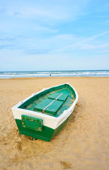 Green boat in the sand on the beach