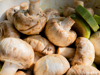 Fresh mushrooms and green courgettes lie in a plate. Cooking vegetarian food