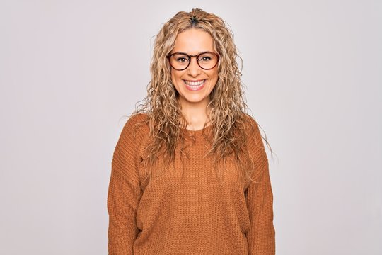 Young beautiful blonde woman wearing casual sweater and glasses over white background with a happy and cool smile on face. Lucky person.