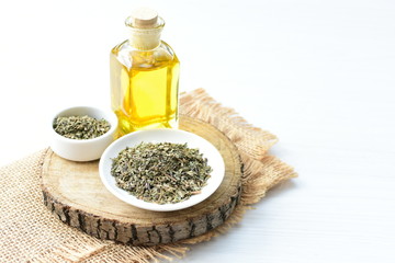 Dried chopped leaves of basil leaves and olive oil on white wooden background