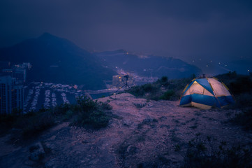 Man traveler Taking photo on top of mountains near of tent camping gear,Male hiking at Yuk Kwai Shan (Mount Johnson) located in Ap Lei Chau,Hong Kong, People living healthy active lifestyle outdoors