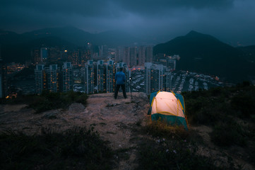 Man traveler Taking photo on top of mountains near of tent camping gear,Male hiking at Yuk Kwai Shan (Mount Johnson) located in Ap Lei Chau,Hong Kong, People living healthy active lifestyle outdoors