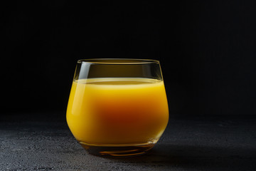 Glass with fresh orange juice on a dark background.