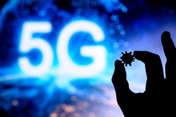 Hands silhouette holds covid 19 virus, tittle 5G in background. Conspiracy theory concept photo