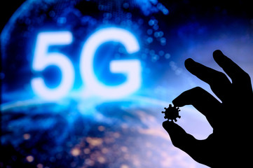 Hands silhouette holds covid 19 virus, tittle 5G in background. Conspiracy theory concept photo