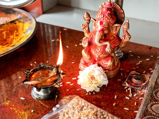 Ganesha idol close up with lit oil lamp