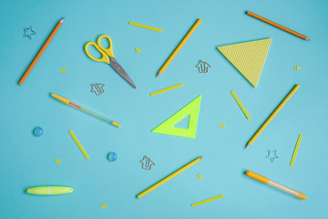 Stationery on blue. Bright stylish flat lay. Different yellow tools with copy space in centre.