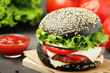 A black burger with vegetables and beef meat	