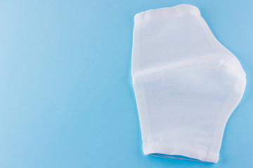 White antivirus mask. Protective gauze mask on a blue background. Handmade medical protective mask from cotton. Protective face mask made of gauze. Top view. Copy space