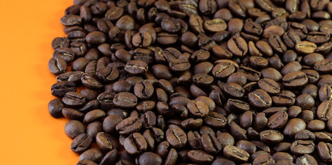 Coffee beans on a bright background. Coffee granules on an orange table. Texture of coffee beans.