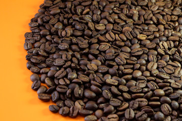 Coffee beans on a bright background. Coffee granules on an orange table. Texture of coffee beans.