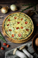 Homemade cheesy spinach quiche for brunch. set on wooden cafe table background.