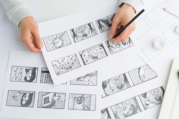 Hands of the artist draw a storyboard on paper. Storytelling. Story frames with heroes.