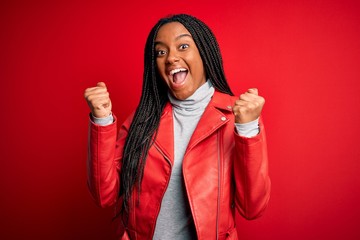 Young african american woman wearing cool fashion leather jacket over red isolated background...