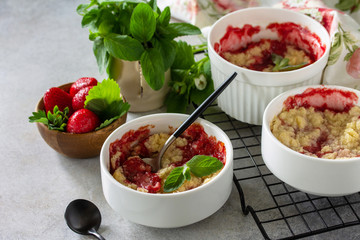 Homemade summer dessert. Strawberries crumble in baking dish on a tabletop made of stone or slate.