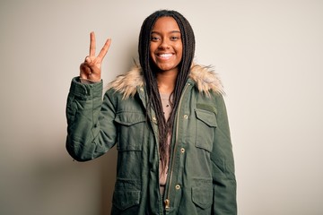 Young african american woman wearing winter parka coat over isolated background showing and pointing up with fingers number two while smiling confident and happy. © Krakenimages.com