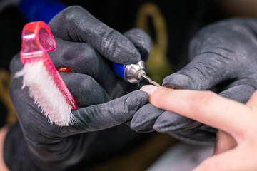 Woman use electric nail file drill in beauty salon. Nails manicure process in detail. Gel polish close-up concept.