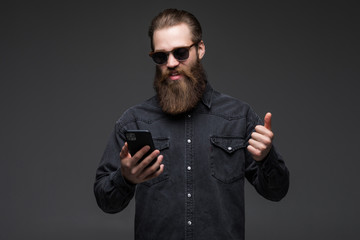 Excited cheerful man wearing shirt using mobile phone celebrating isolated over gray background