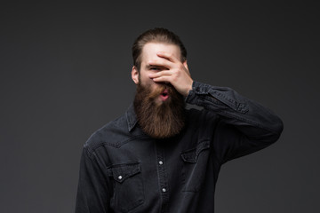 Fototapeta premium Young man with hand on face covering eyes for surprise standing over isolated gray background . Blind concept.