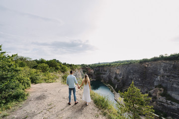 Beautiful woman and man hug and kiss near the canyon.