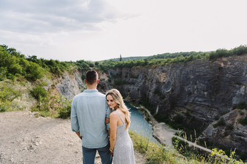 Beautiful woman and man hug and kiss near the canyon.