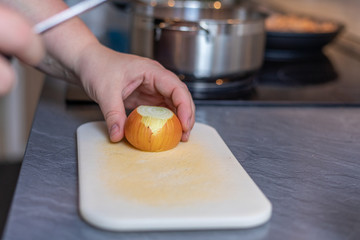 Cropped Hands Of Woman Cutting Onion On Cutting Board At Table