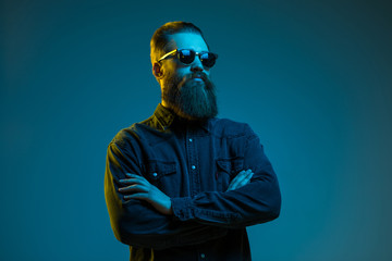 Handsome bearded hipster man wearing round sunglasses Isolated over blue light background